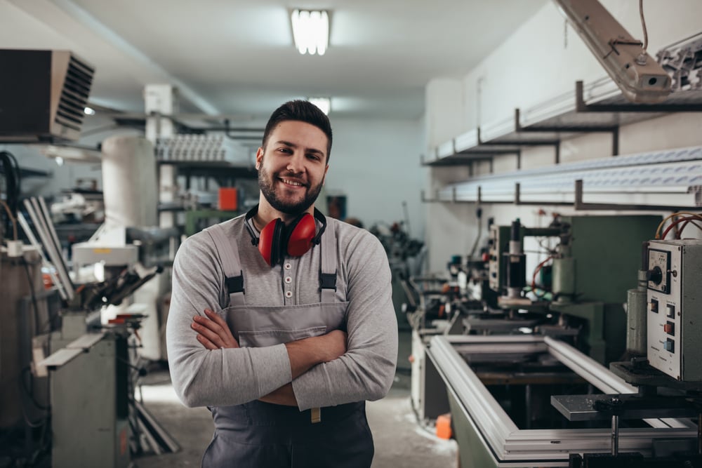Smiling industrial worker in a workshop wearing overalls